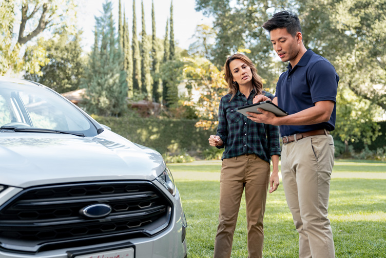 Safeco claims adjuster speaks with woman in front of her car.