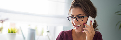 Woman speaks on her mobile phone while working from her laptop computer.