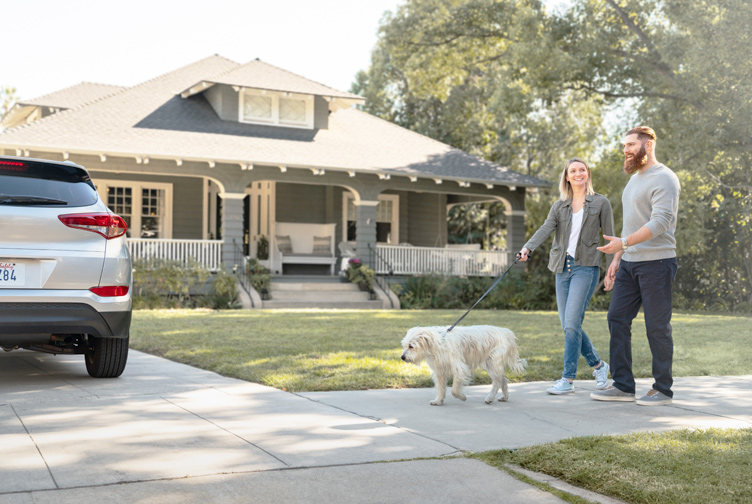 Family walks their dog in front of their home.
