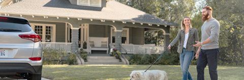 Family walks their dog in front of their home.